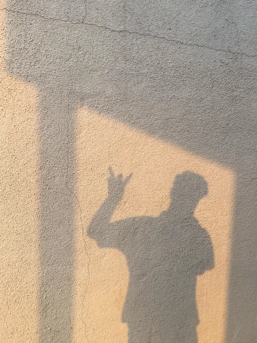 Sombra de uma pessoa com a mão erguida sobre uma parede